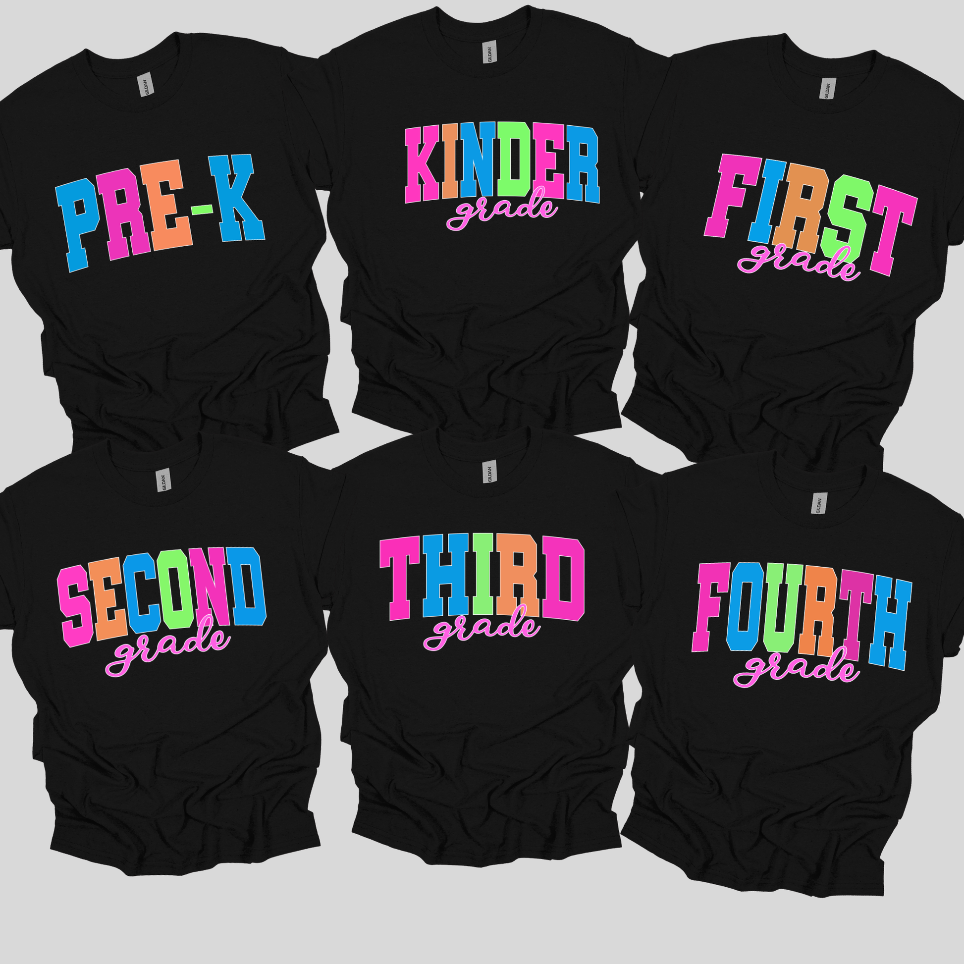 Six black short-sleeve T-shirts arranged in two rows on a light gray background, each printed with colorful grade text: Pre-K, Kinder, First, Second, Third, and Fourth.