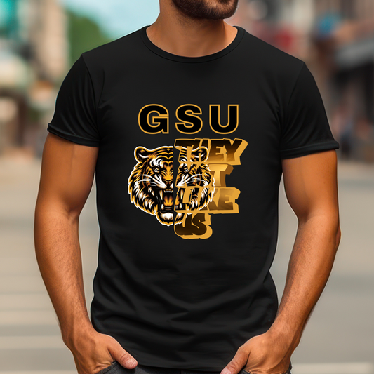 Person wearing a black t-shirt with a gold tiger graphic and text. Grambling State Tigers T-Shirt - They Not Like Us - Game Day Statement Tee