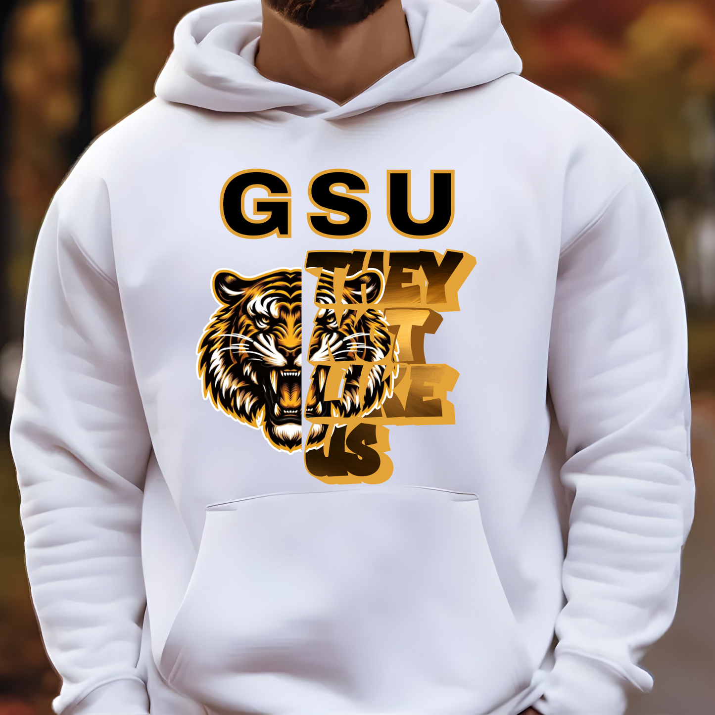 A white pullover hoodie worn by a person, featuring a large front graphic with the text 'GSU THEY'RE COMING' and a tiger illustration in black and gold.