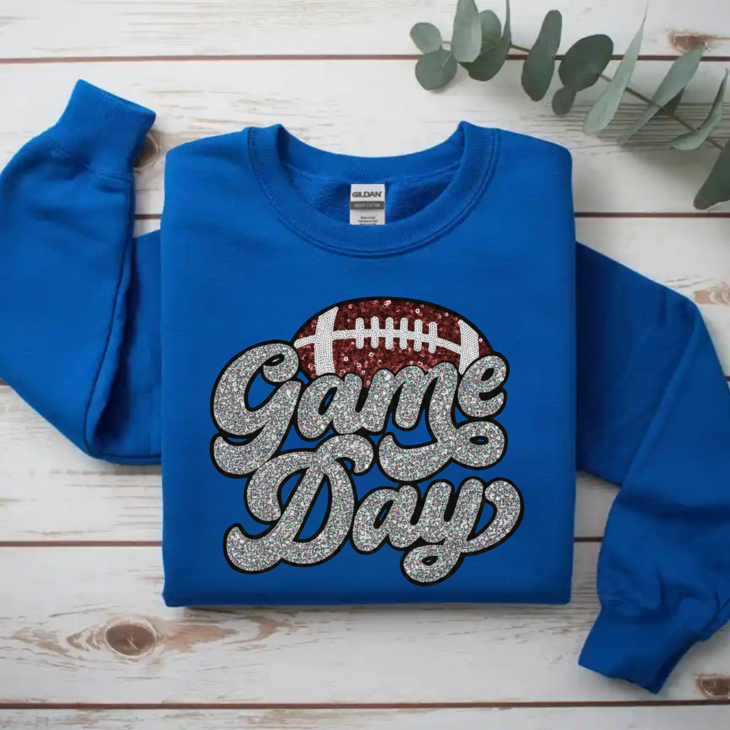 Blue sweatshirt with 'Game Day' text and football graphic on a wooden surface