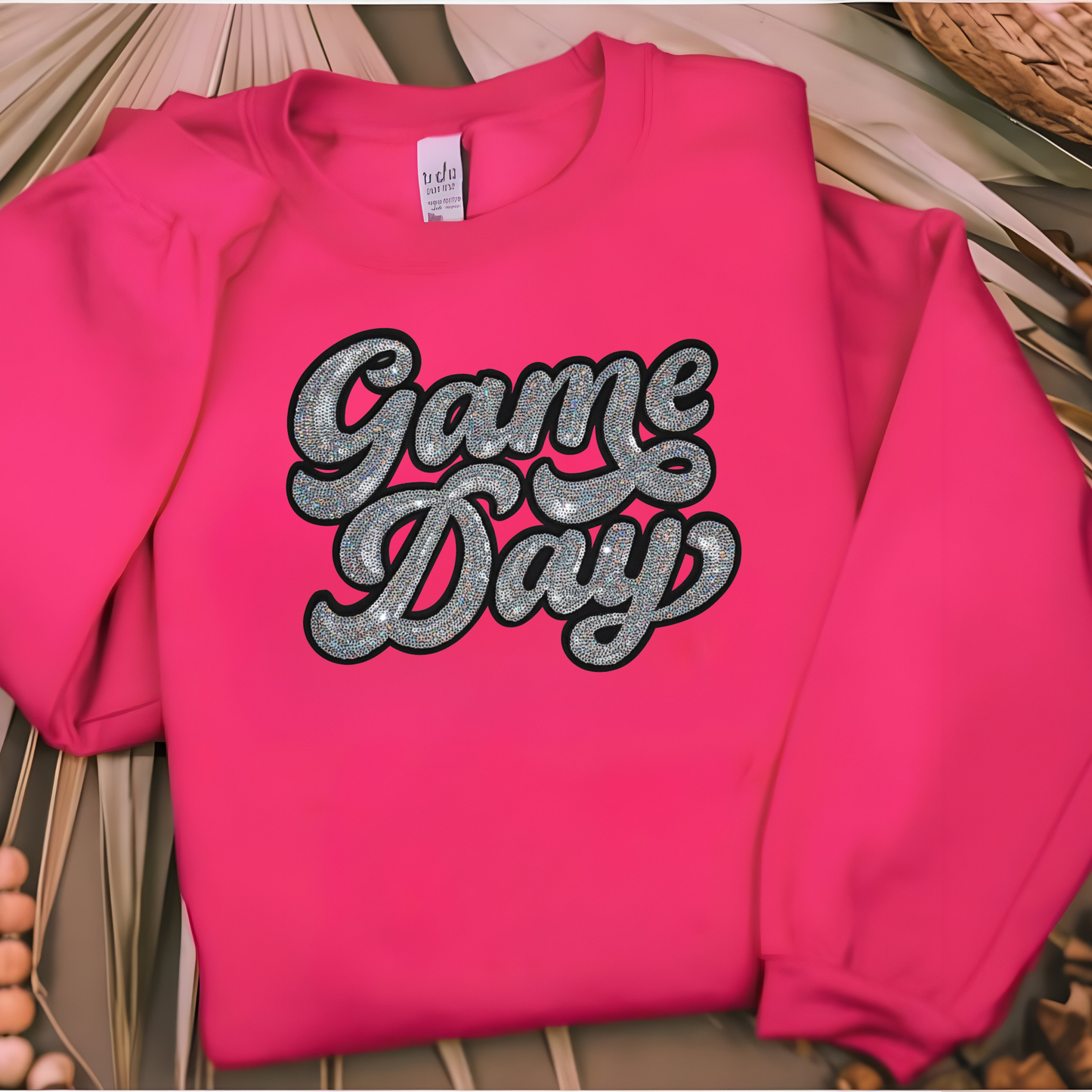 Pink sweatshirt with 'Game Day' text on a wooden surface
