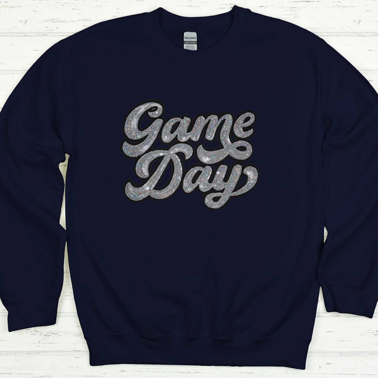 Navy blue sweatshirt with 'Game Day' text in silver on a white wooden background