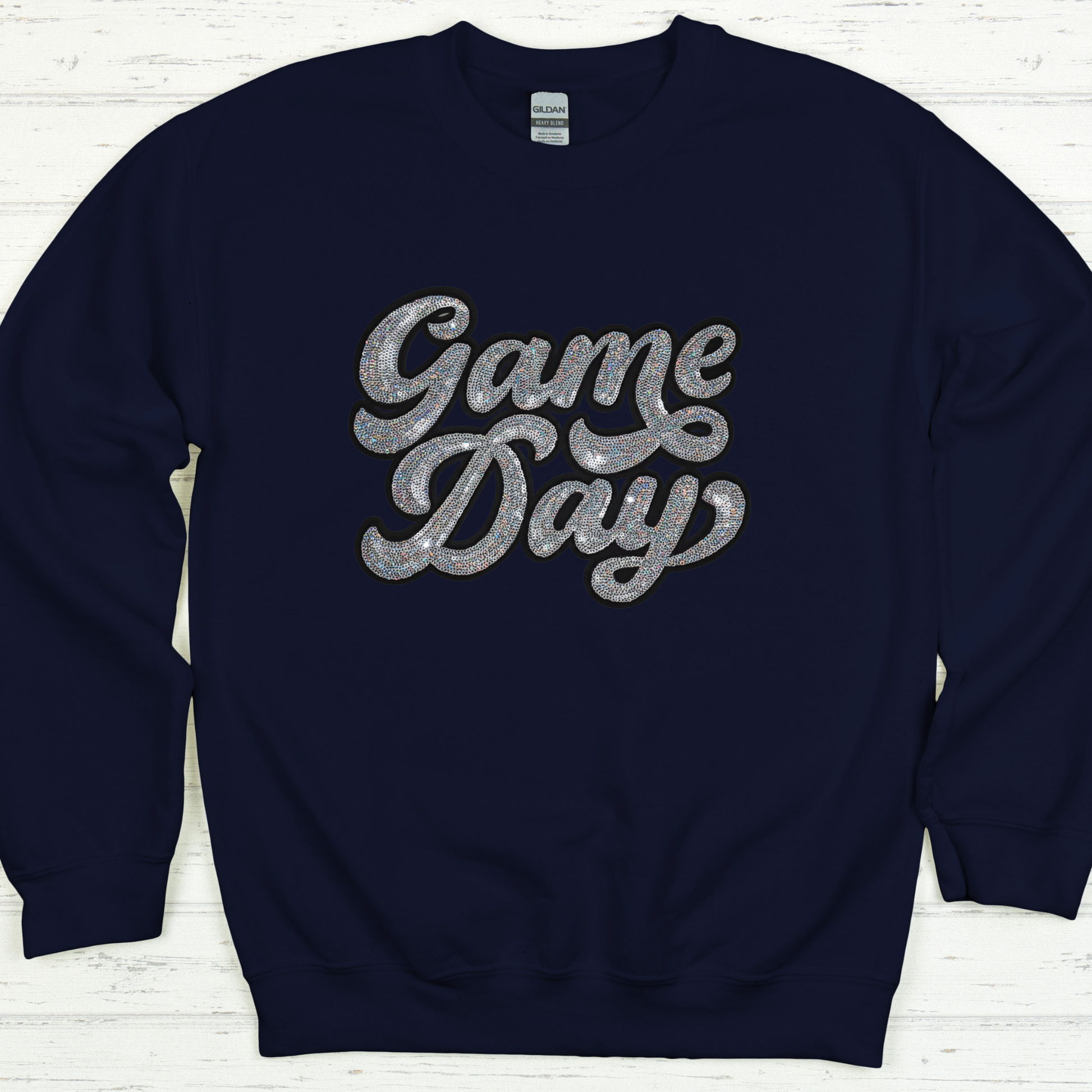 Navy blue sweatshirt with 'Game Day' text in silver on a white wooden background