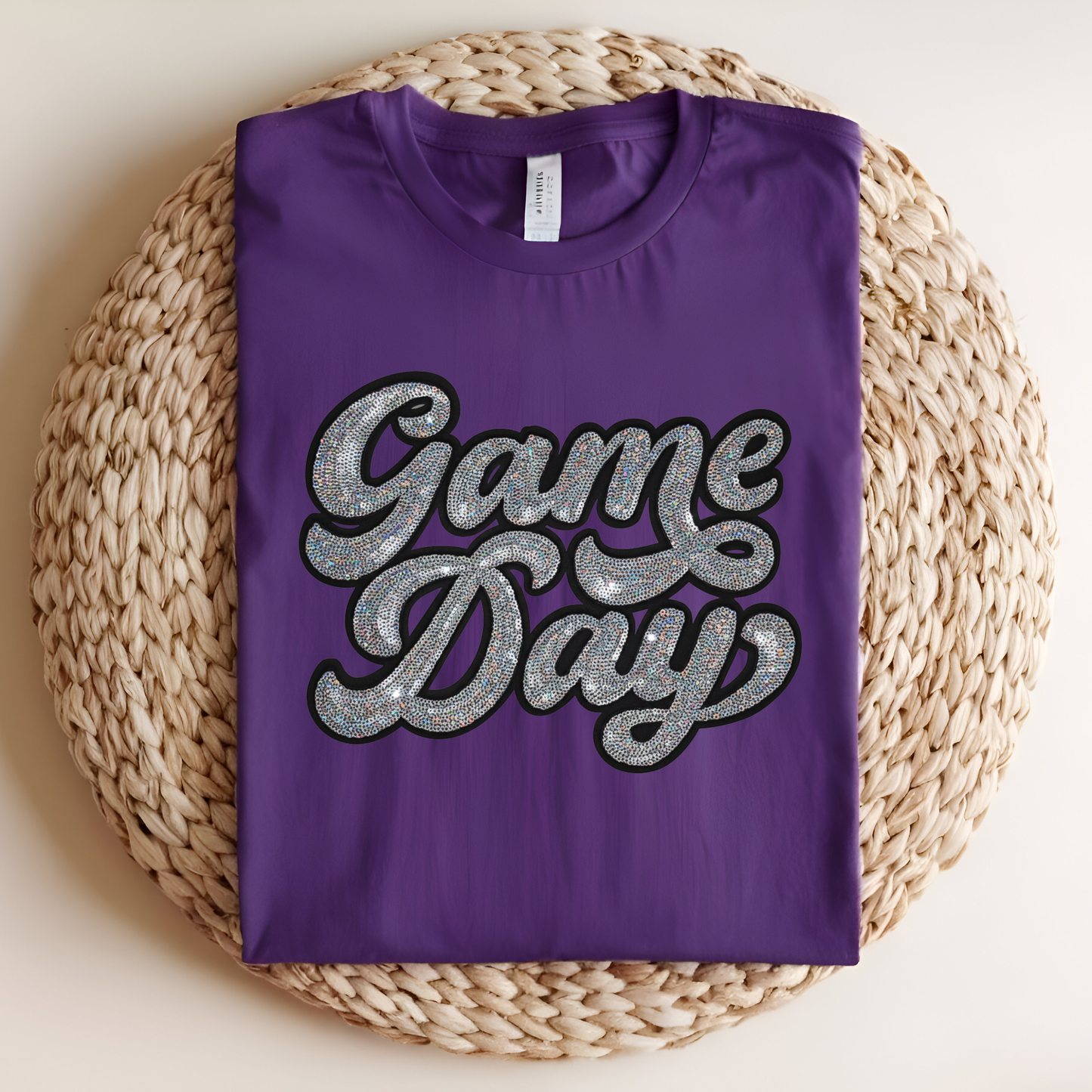 Purple t-shirt with 'Game Day' text on a woven mat
