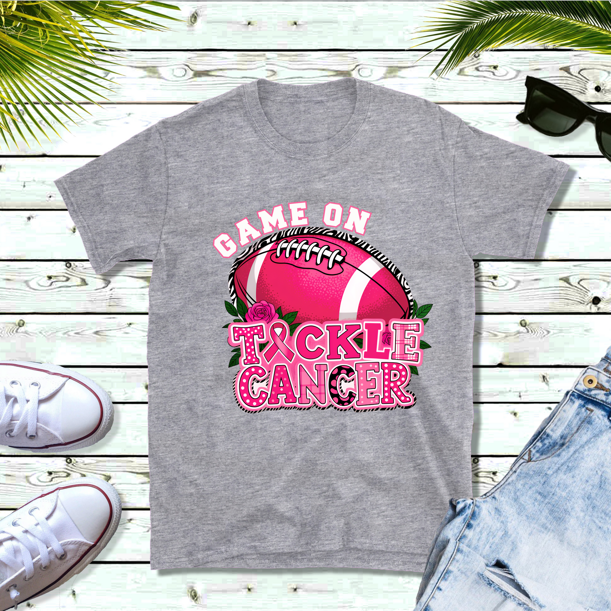 Gray t-shirt with 'Game On Tackle Cancer' design featuring a pink football on a wooden surface. Pink Out Football T-Shirt:  Game On Tackle Awareness Support Tee