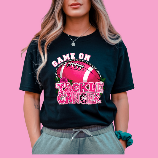 Person wearing a black t-shirt with 'Tackle Cancer' design on a pink background Pink Out Football T-Shirt:  Game On Tackle Awareness Support Tee