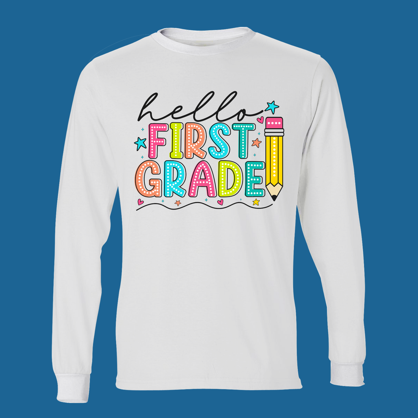 A white long-sleeve t-shirt with a colorful 'Hello First Grade' graphic on the chest, displayed against a solid blue background.