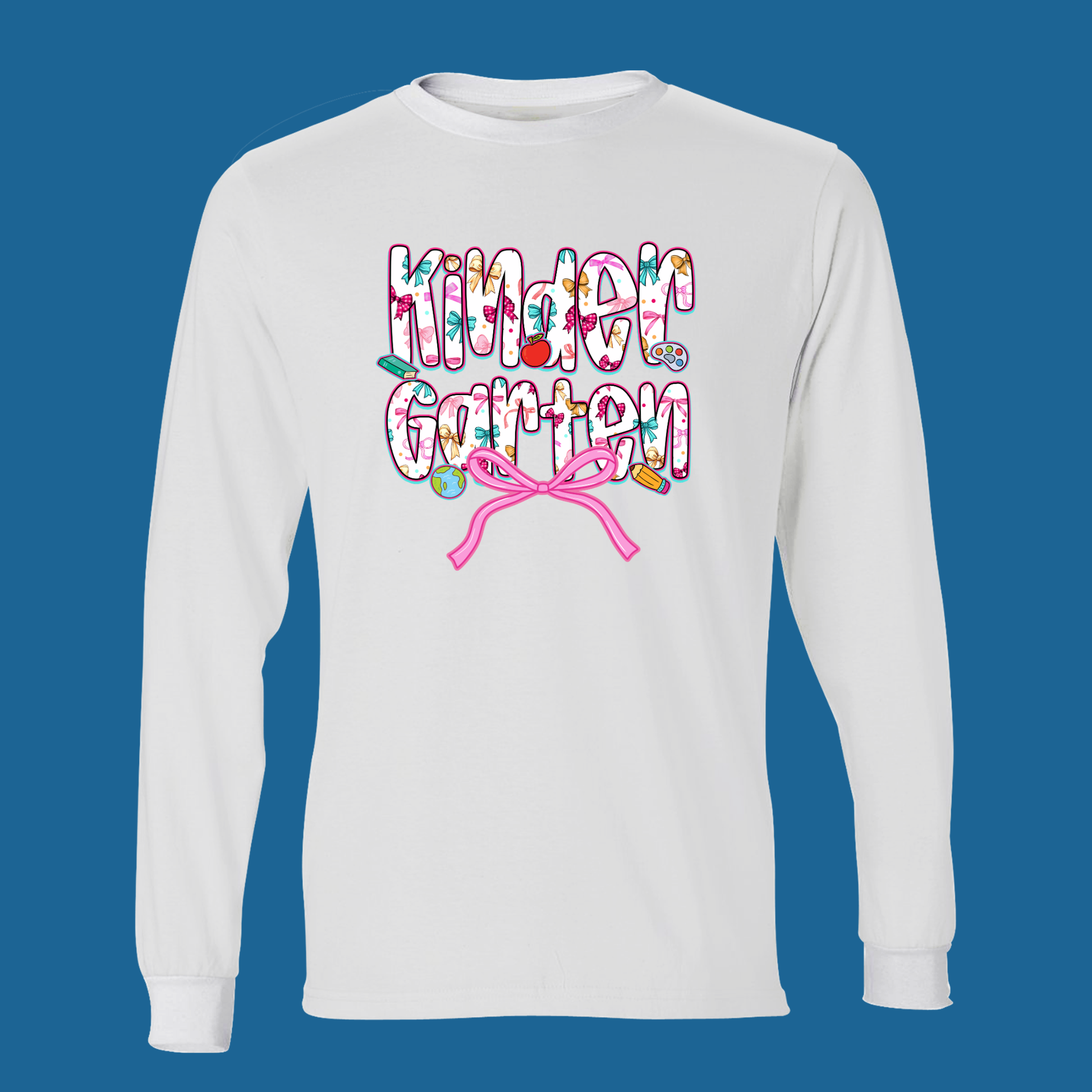 A white long-sleeve t-shirt with a colorful graphic on the chest reading 'Kinder Garten' in a floral pattern, decorated with small gardening icons and a pink ribbon bow underneath, set against a solid blue background.