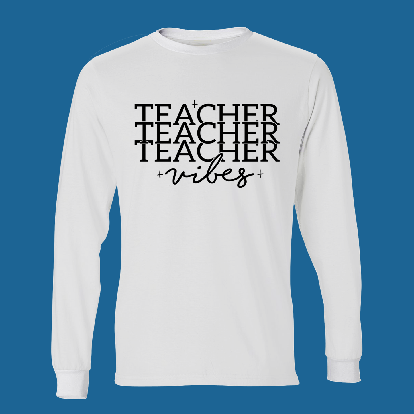 A white long-sleeve crewneck t-shirt with a black graphic text print reading 'TEACHER TEACHER TEACHER vibes' on the chest, displayed against a solid blue background.