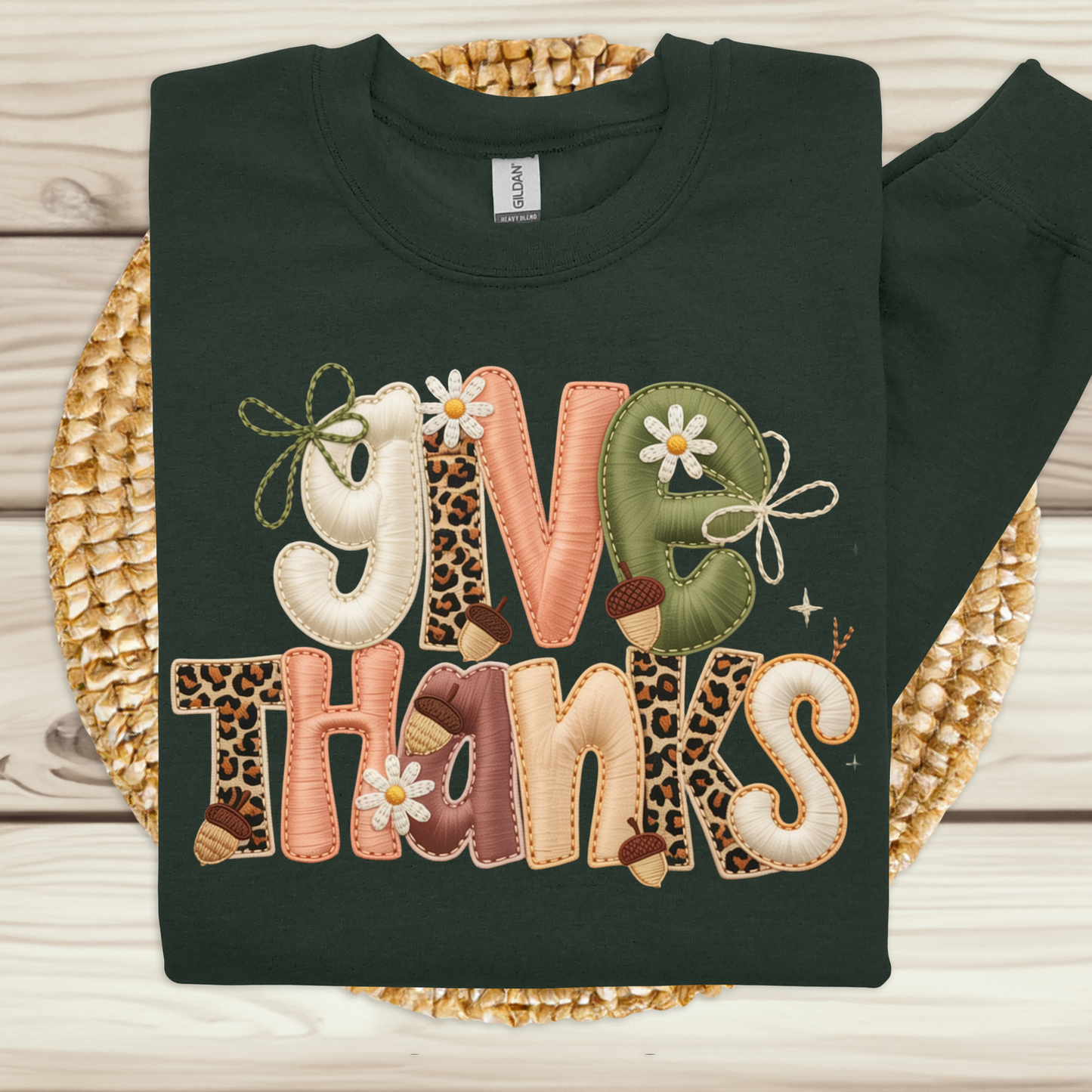 Black sweatshirt with 'Give Thanks' text in colorful letters on a woven mat.