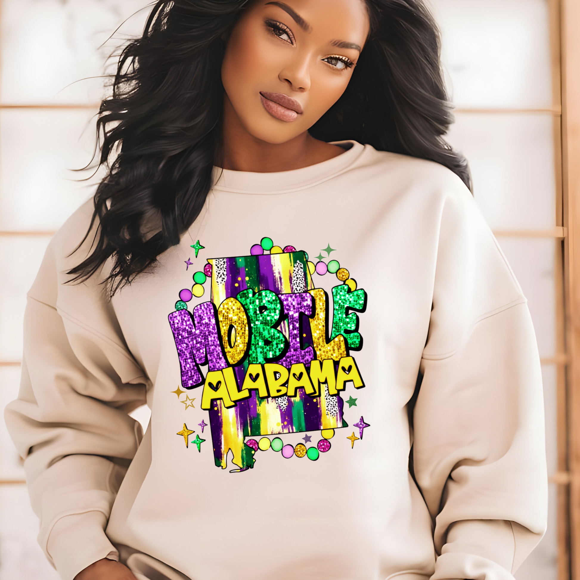 Woman wearing a beige sweatshirt with 'Mobile, Alabama' design.