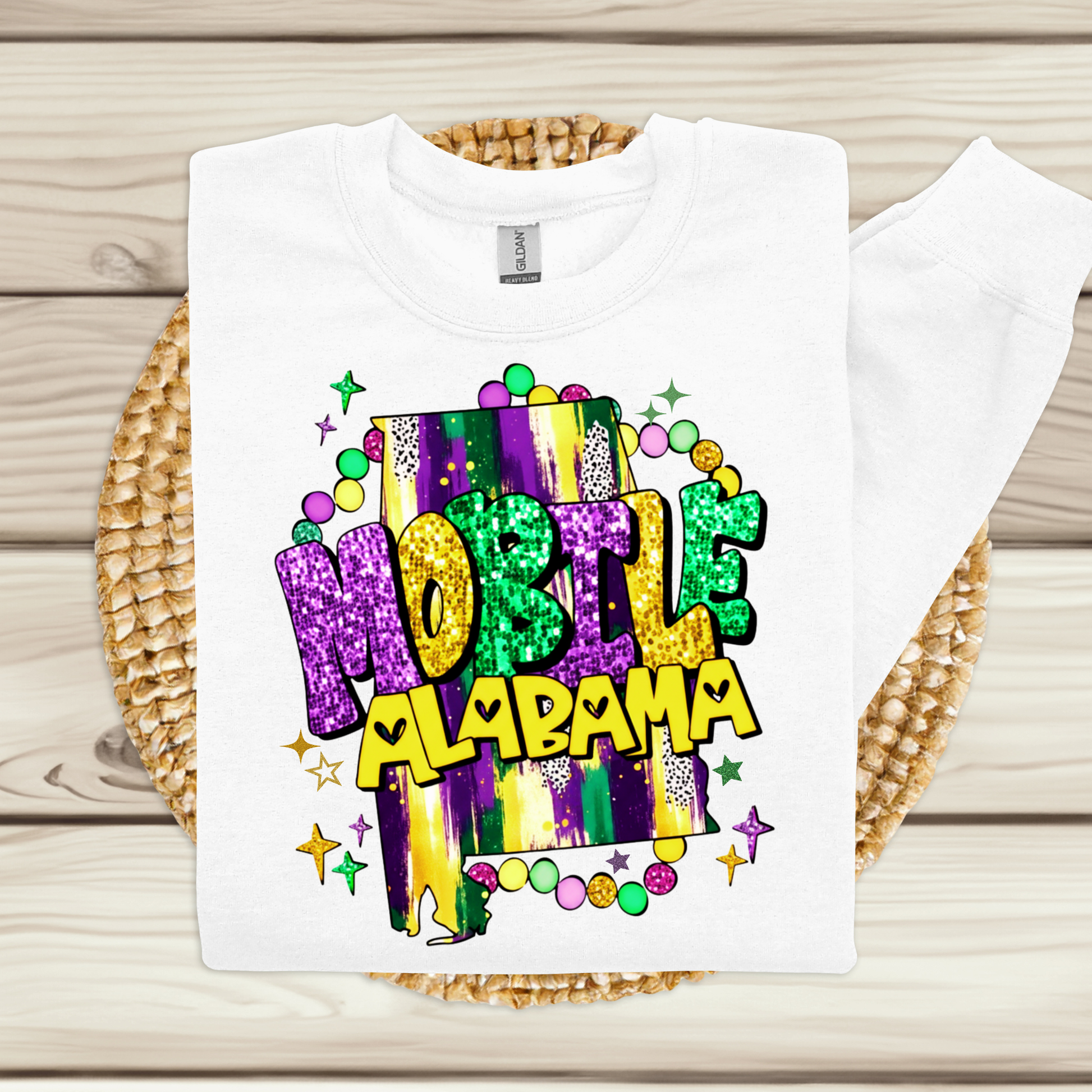 White t-shirt with colorful 'Mobile Alabama' design on a wooden surface