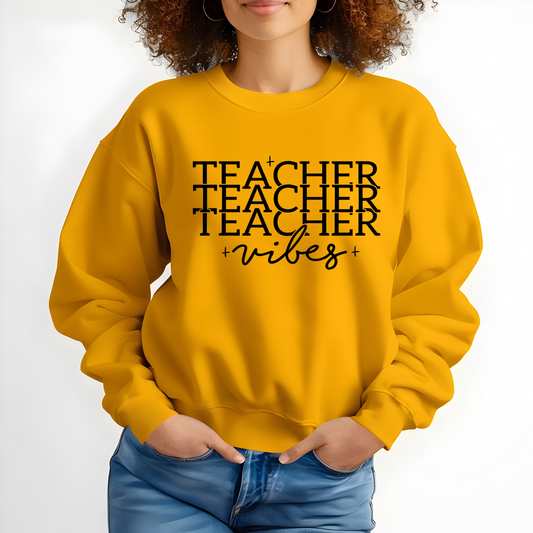 A woman wearing a mustard yellow crewneck sweatshirt with the black printed text 'TEACHING is my Super POWER' on the front, paired with blue jeans against a plain white background.