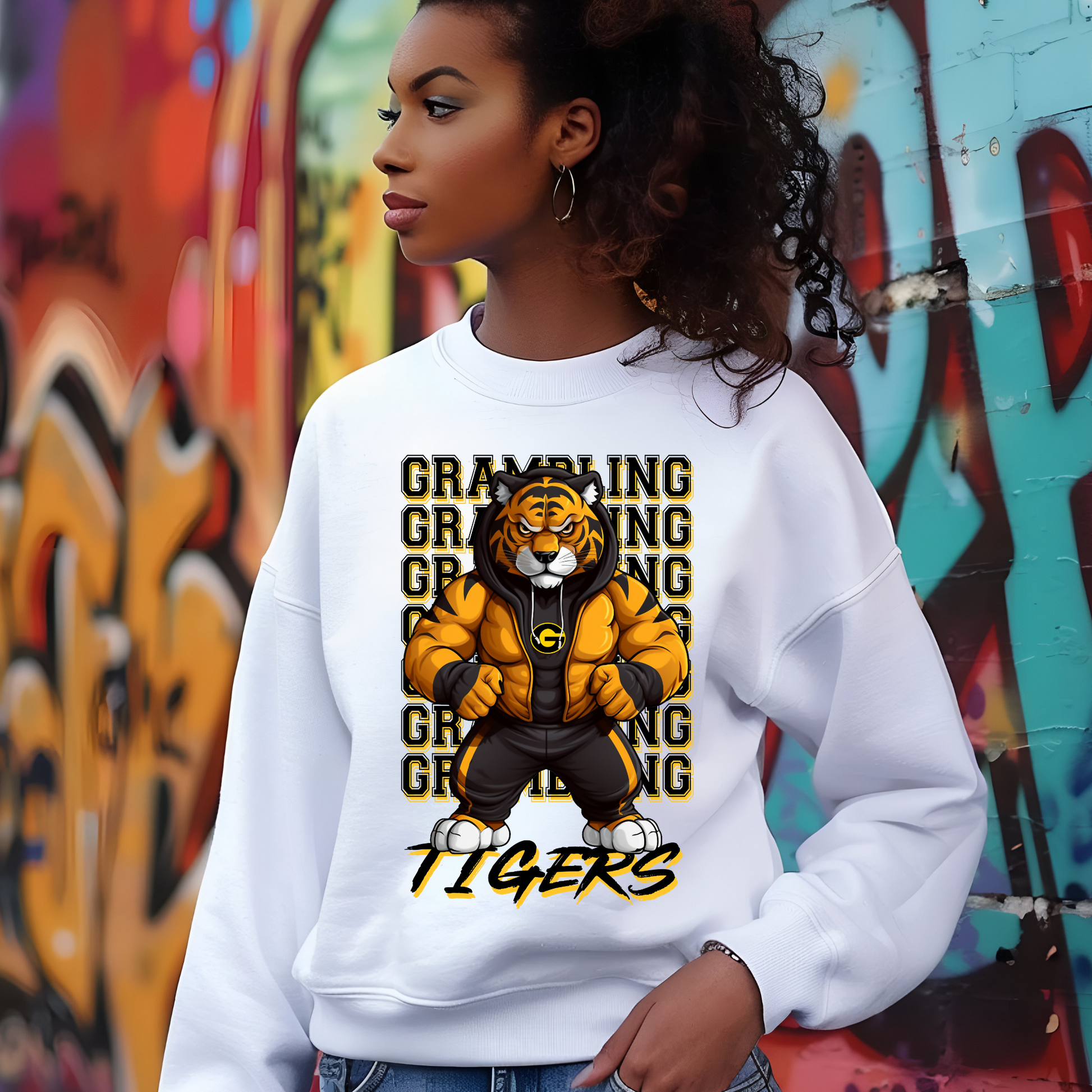 Person wearing a white sweatshirt with a tiger graphic and 'GRABBING TIGERS' text against a graffiti-covered wall.