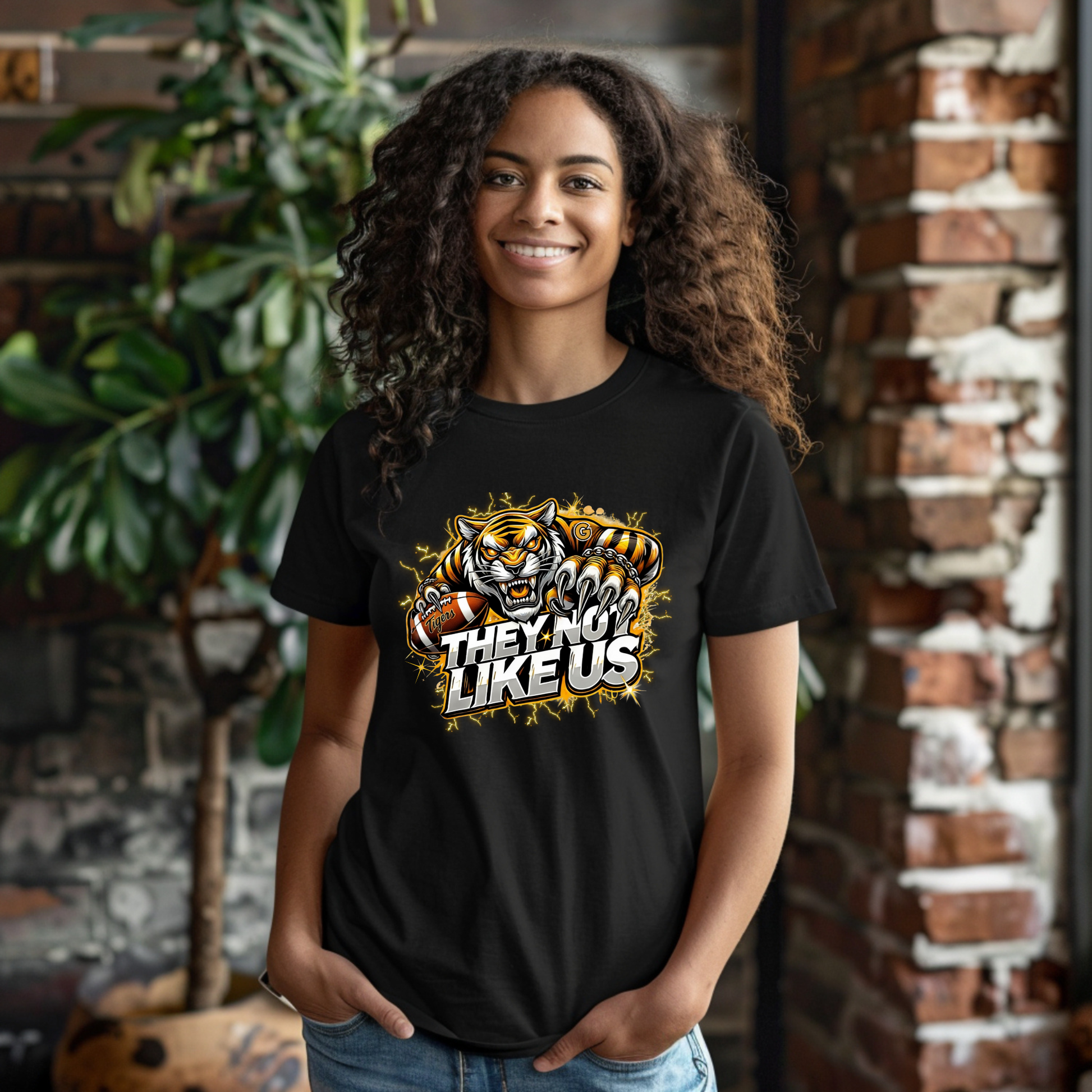 Person wearing a black t-shirt with a tiger graphic and text, standing in front of a brick wall.