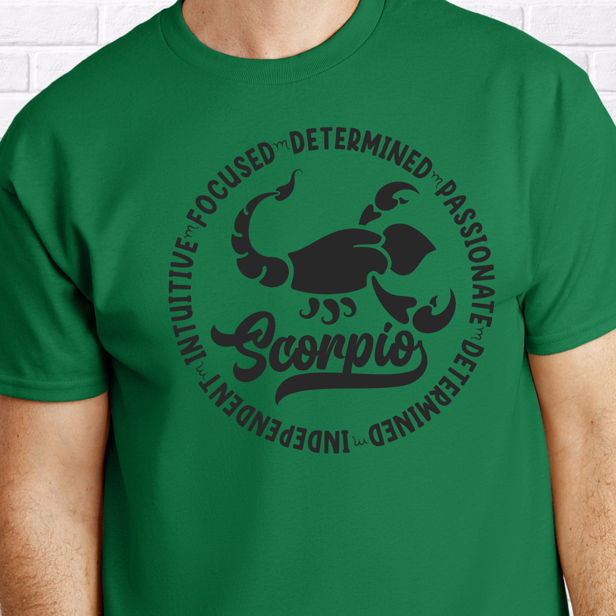 man wearing a black crewneck sweatshirt featuring a white circular Scorpio zodiac graphic with a scorpion illustration, the word "Scorpio," and trait keywords like intuitive, focused, determined, passionate, and independent.