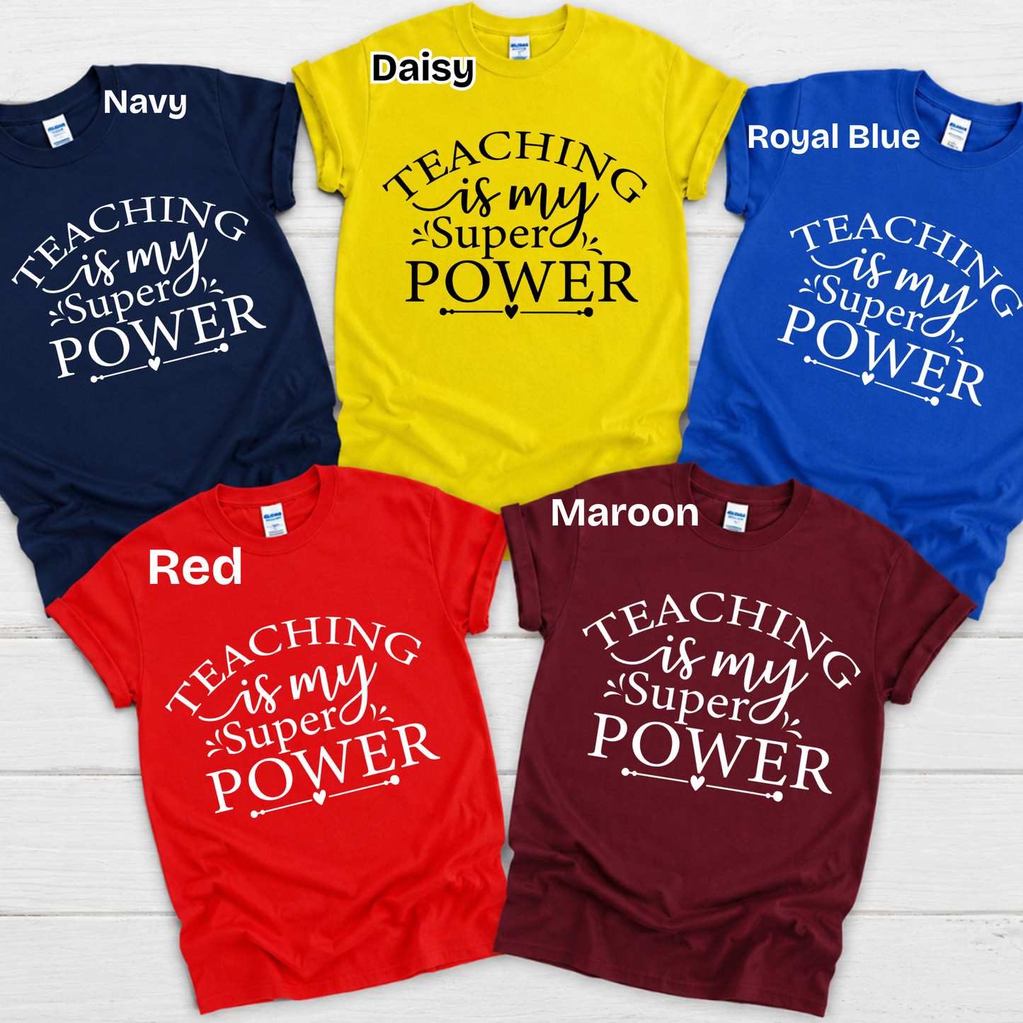 Six graphic t-shirts in different colors (Navy, Daisy yellow, Royal Blue, Red, Maroon) arranged in a circle on a white wood background. Each shirt features the text 'my students BRIGHTEN my day' in contrasting white or black lettering.