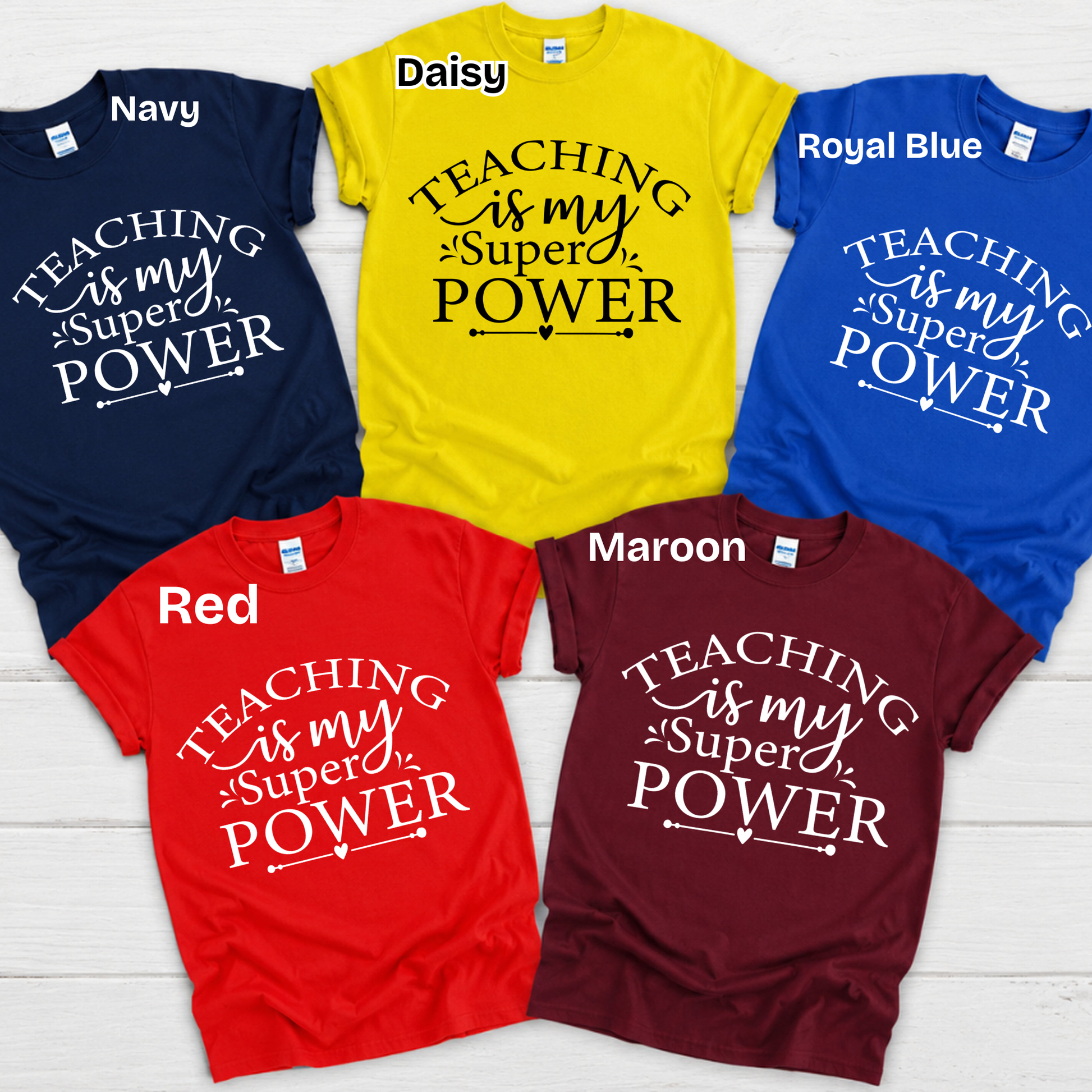 Six graphic t-shirts in different colors (Navy, Daisy yellow, Royal Blue, Red, Maroon) arranged in a circle on a white wood background. Each shirt features the text 'my students BRIGHTEN my day' in contrasting white or black lettering.