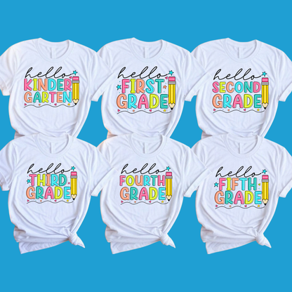 Six white graphic T-shirts arranged in two rows on a bright blue background. Each shirt has a colorful 'hello [grade] grade' design with a pencil and star accents.