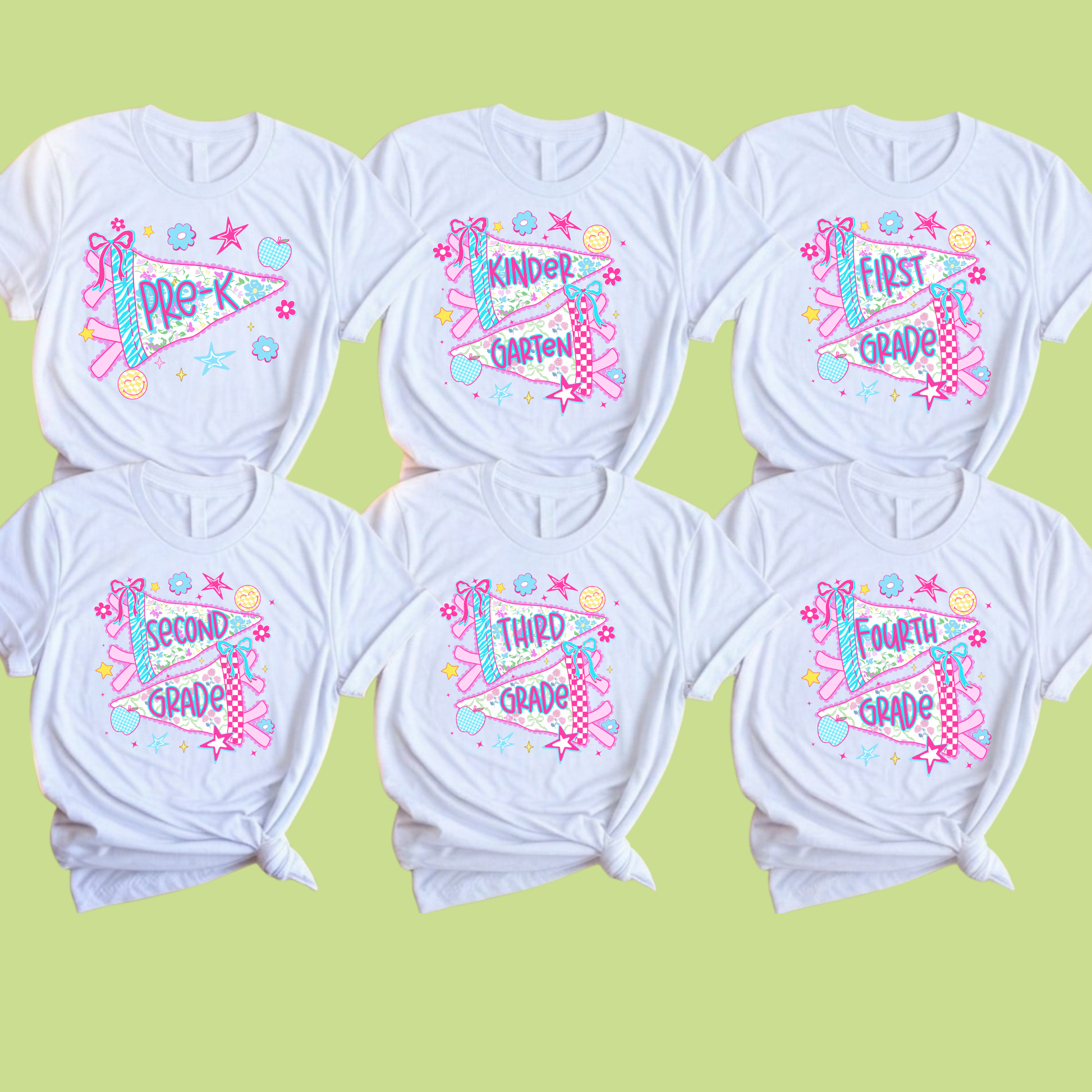 Six white short-sleeve T-shirts arranged in two rows on a pale yellow-green background. Each shirt has a colorful graphic print with school-grade-themed text and playful doodles including stars, hearts, and ribbon motifs.