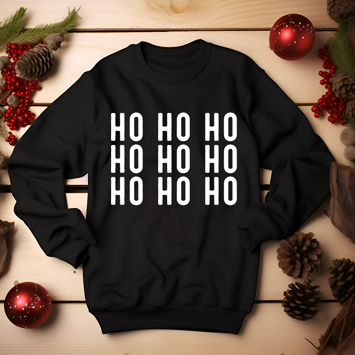 Black sweatshirt with 'HO HO HO' text on a wooden surface with Christmas decorations.