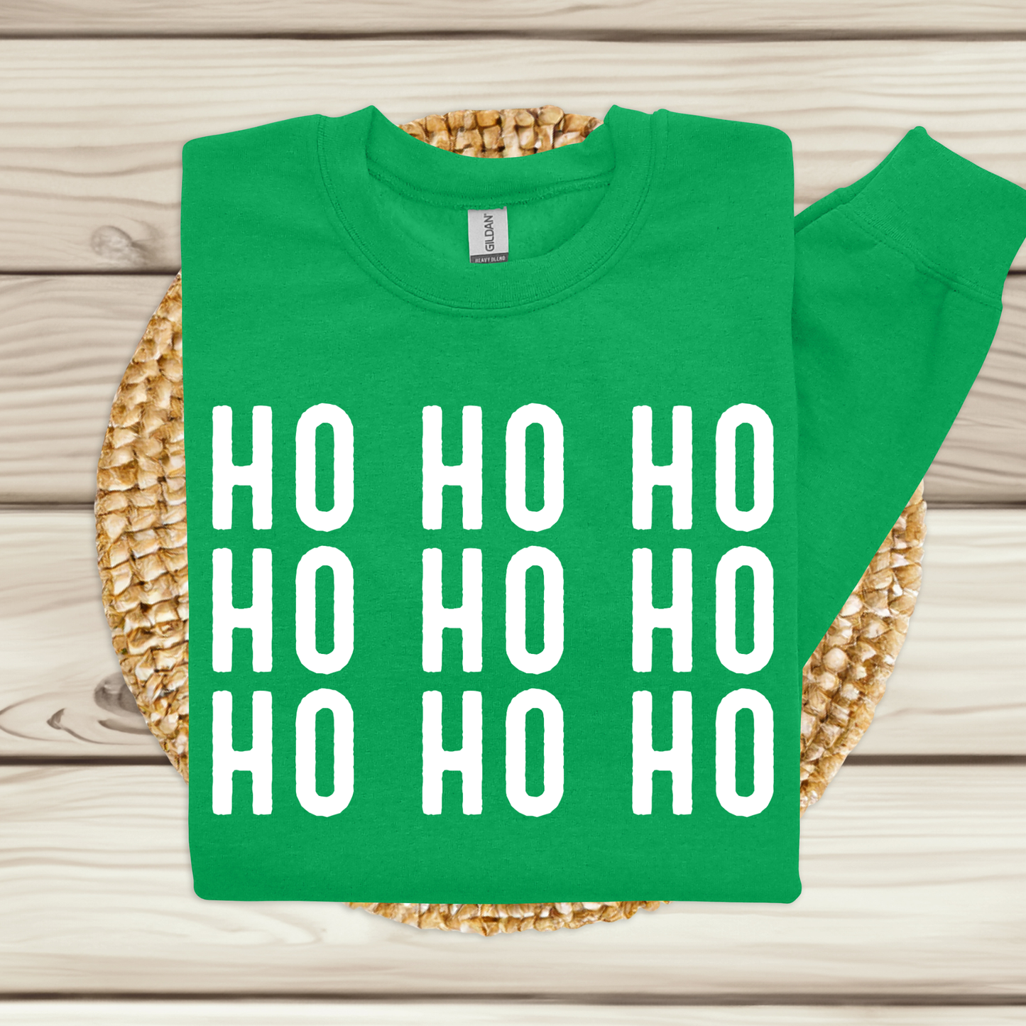 Green t-shirt with 'HO HO HO' text on a woven mat