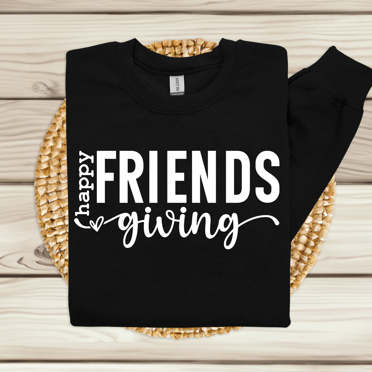 Black sweatshirt with 'happy FRIENDS giving' text on a woven mat