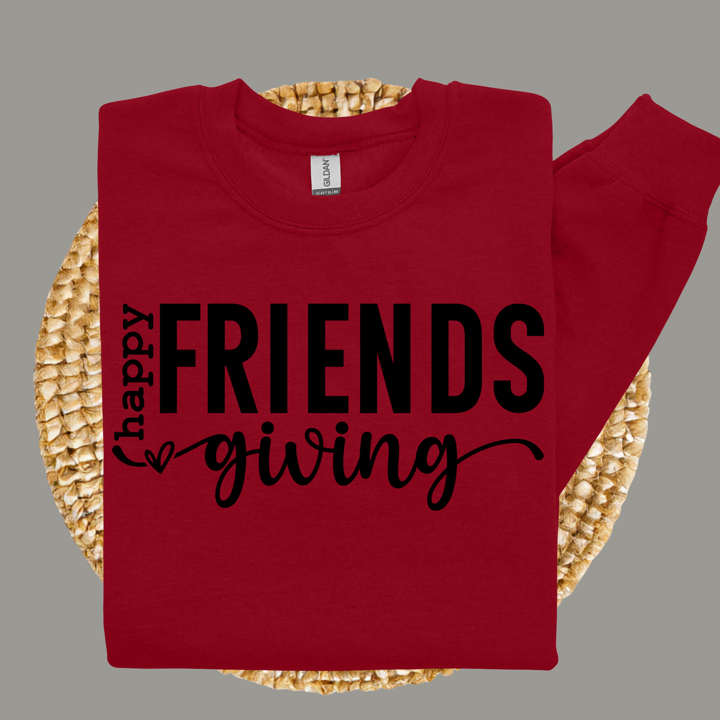 Red shirt with 'happy FRIENDS giving' text on a woven surface