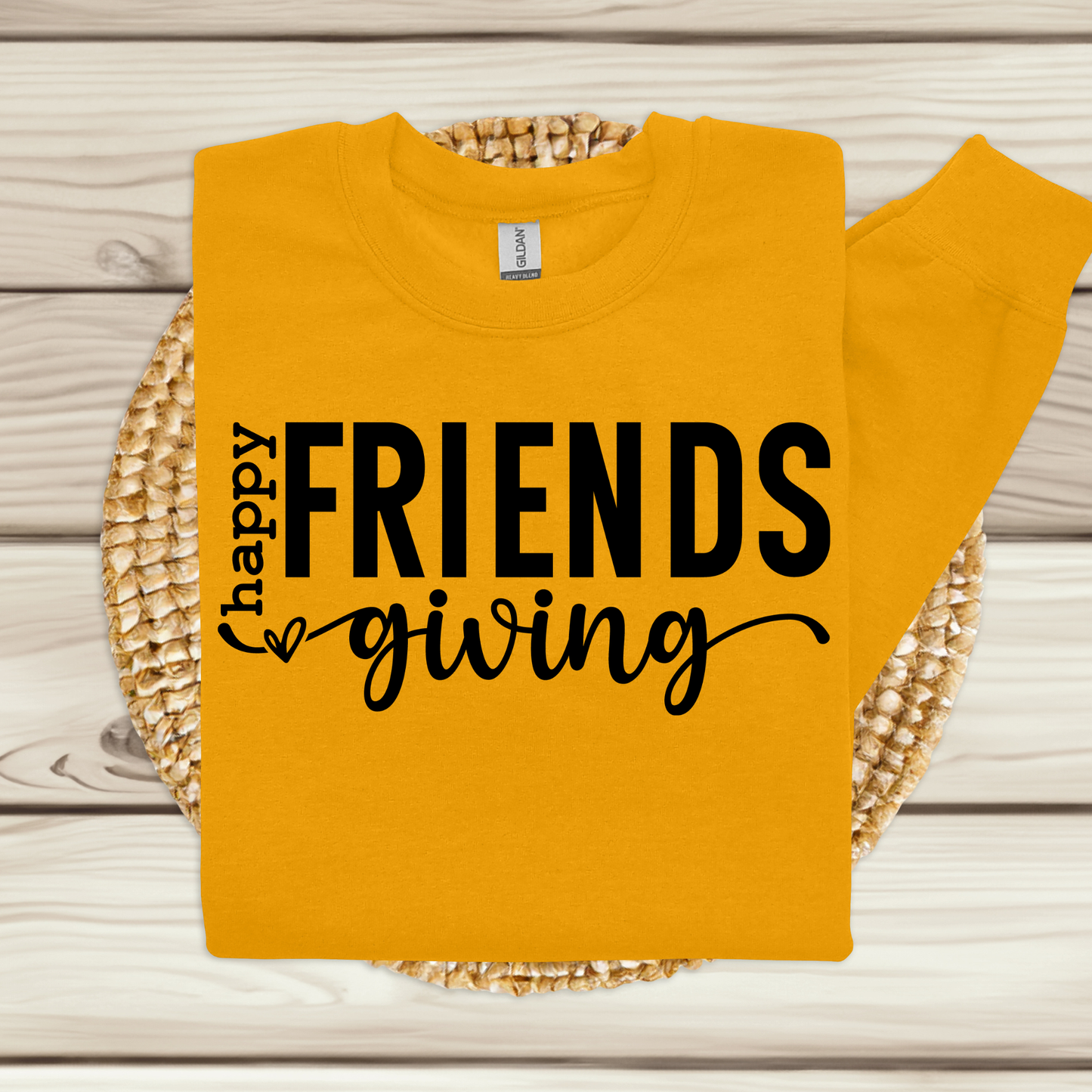 Yellow sweatshirt with 'Happy Friends Giving' text on a wooden surface