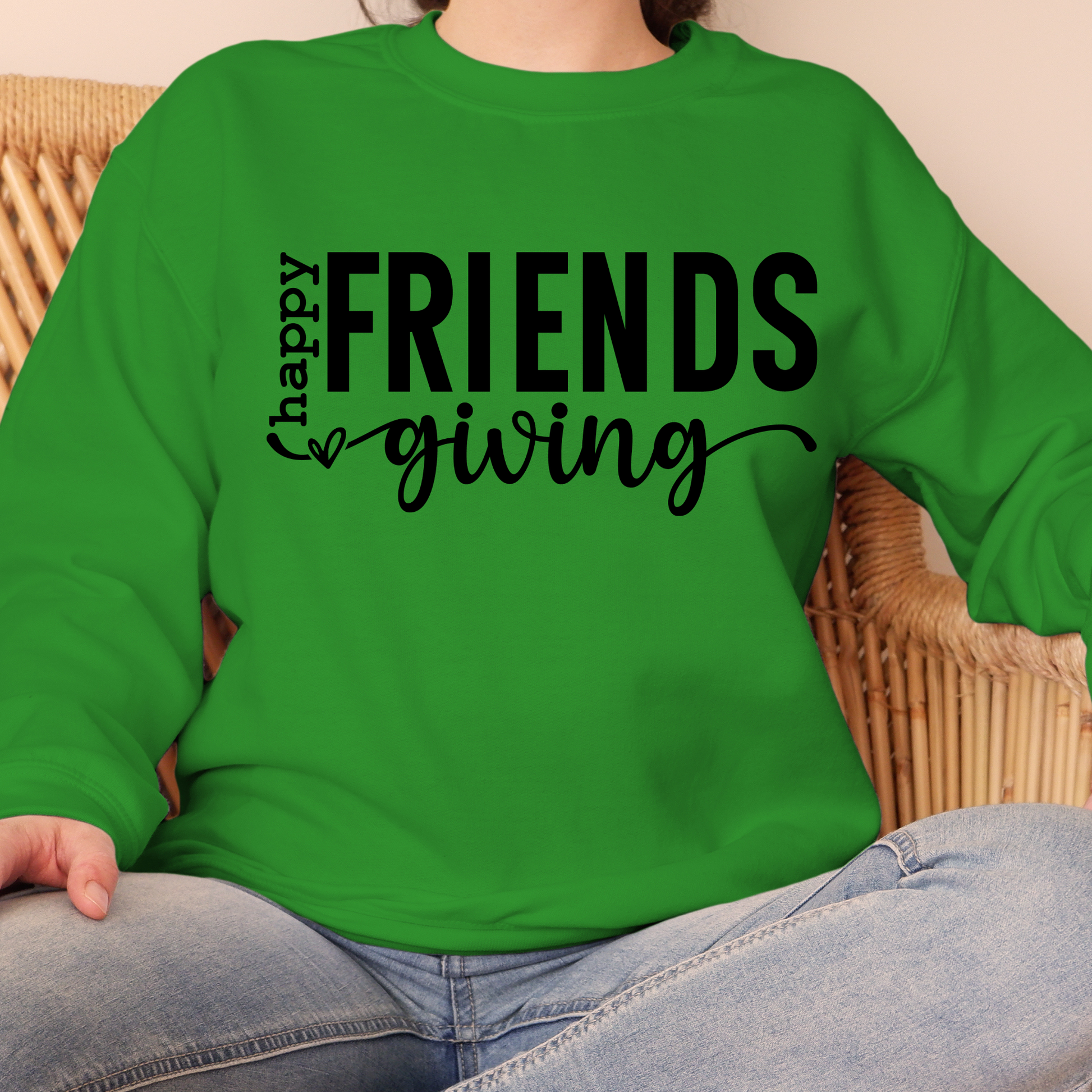 Green sweatshirt with 'happy FRIENDS giving' text worn by a person sitting on a wicker chair.