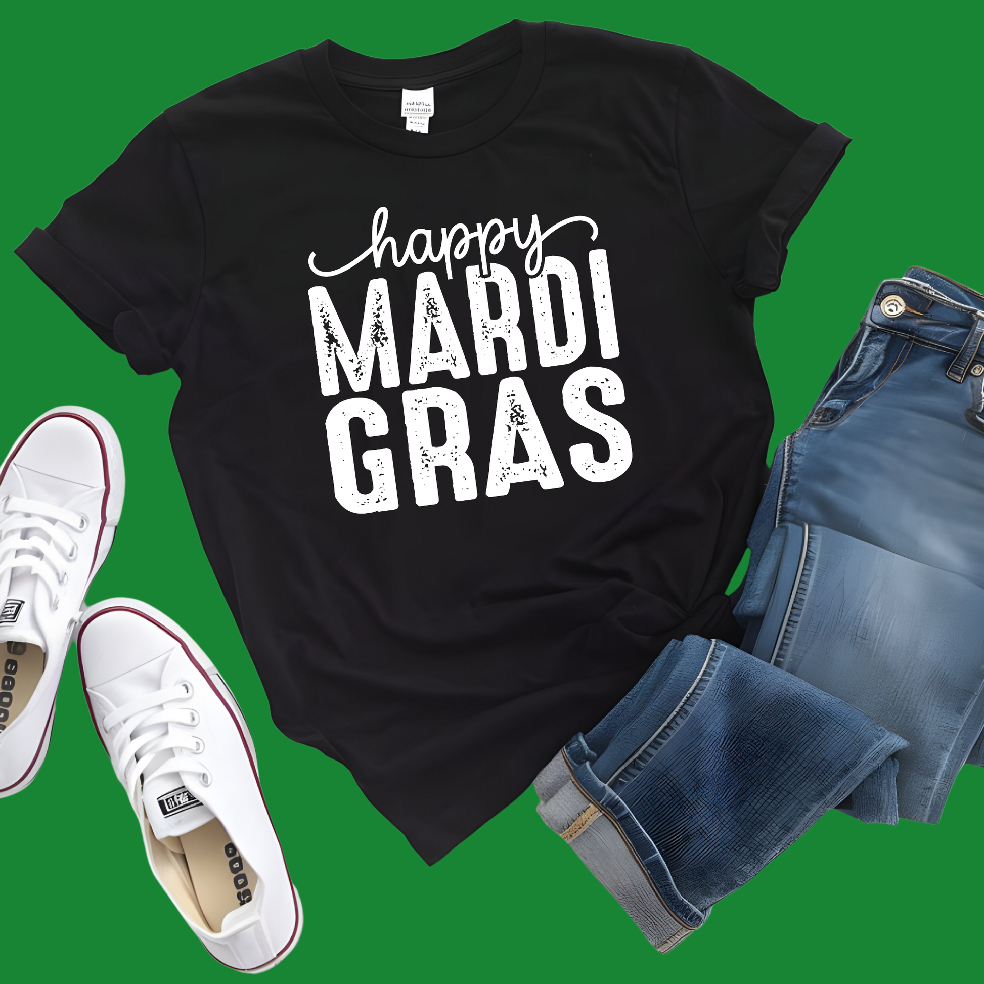 Black t-shirt with 'happy MARDI GRAS' text, white sneakers, and blue jeans on a green background