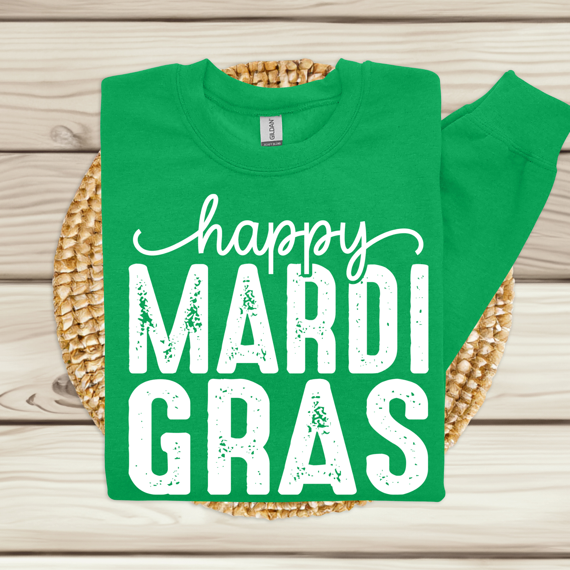 Green t-shirt with 'happy MARDI GRAS' text on a woven mat
