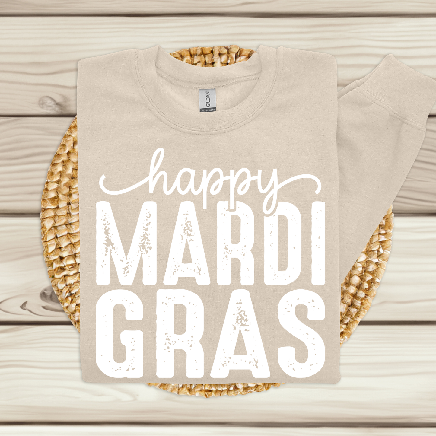 Beige t-shirt with 'happy MARDI GRAS' text on a wooden surface