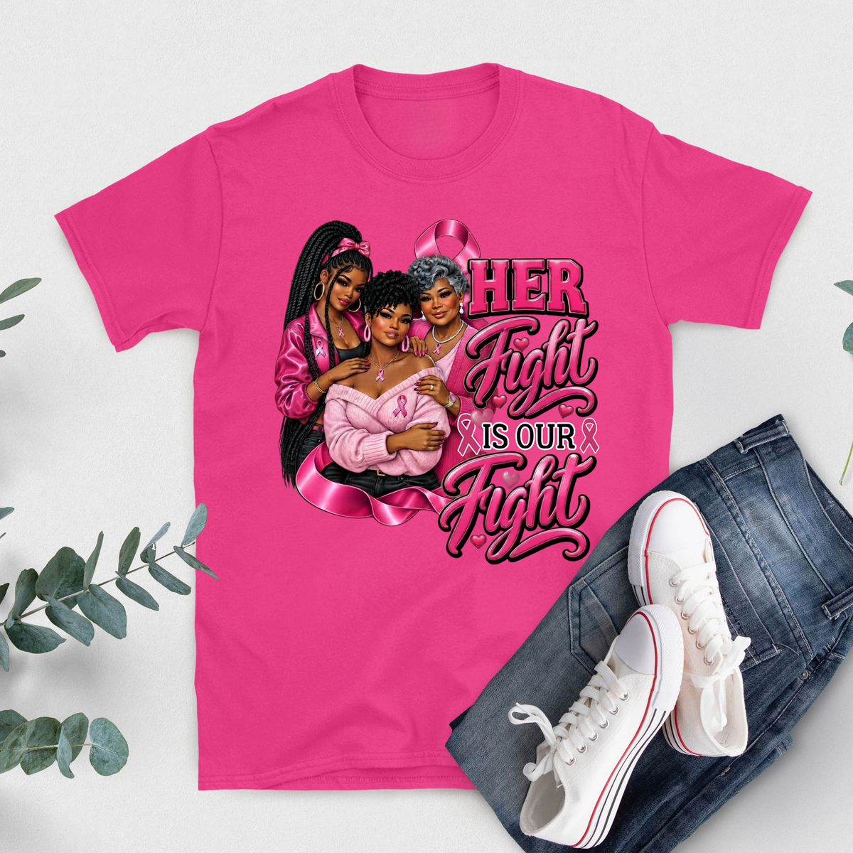 A bright pink graphic T-shirt laid flat on a light gray background, styled with blue jeans and white sneakers. The shirt features a large printed design with three women, a pink ribbon, and the text 'HER Fight IS Our Fight'.