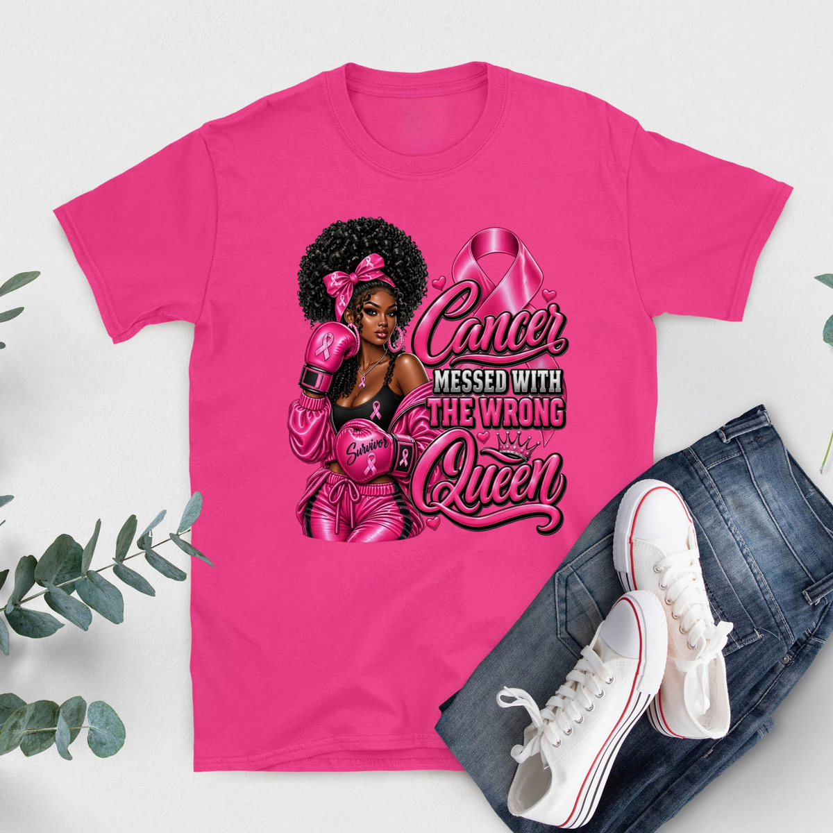 A bright pink graphic T-shirt laid flat on a light gray background, styled with blue jeans and white sneakers. The shirt features a large printed design with three women, a pink ribbon, and the text 'HER Fight IS Our Fight.