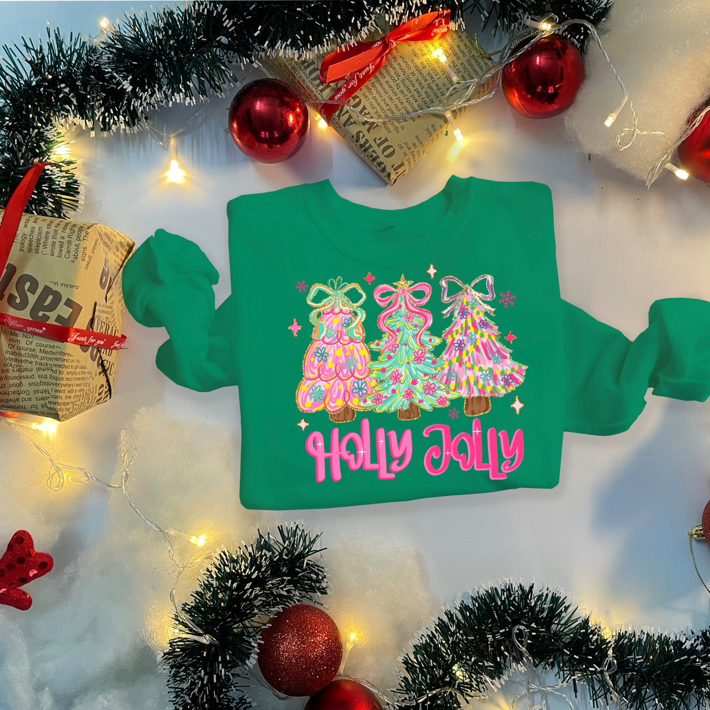 Green sweatshirt with Christmas tree design and 'Holly Jolly' text, surrounded by festive decorations.