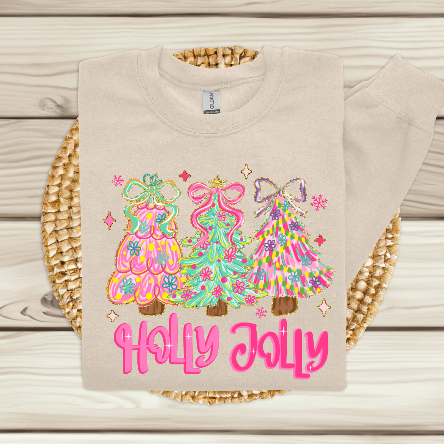 Beige sweatshirt with colorful Christmas tree designs and 'Holly Jolly' text on a wooden surface.