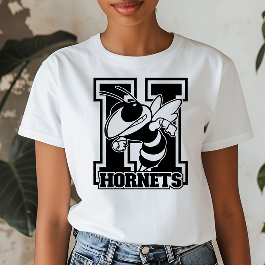 A woman wearing a white short-sleeve t-shirt with a black and white graphic of a hornet mascot and the word 'HORNETS' on the front, paired with blue jeans.