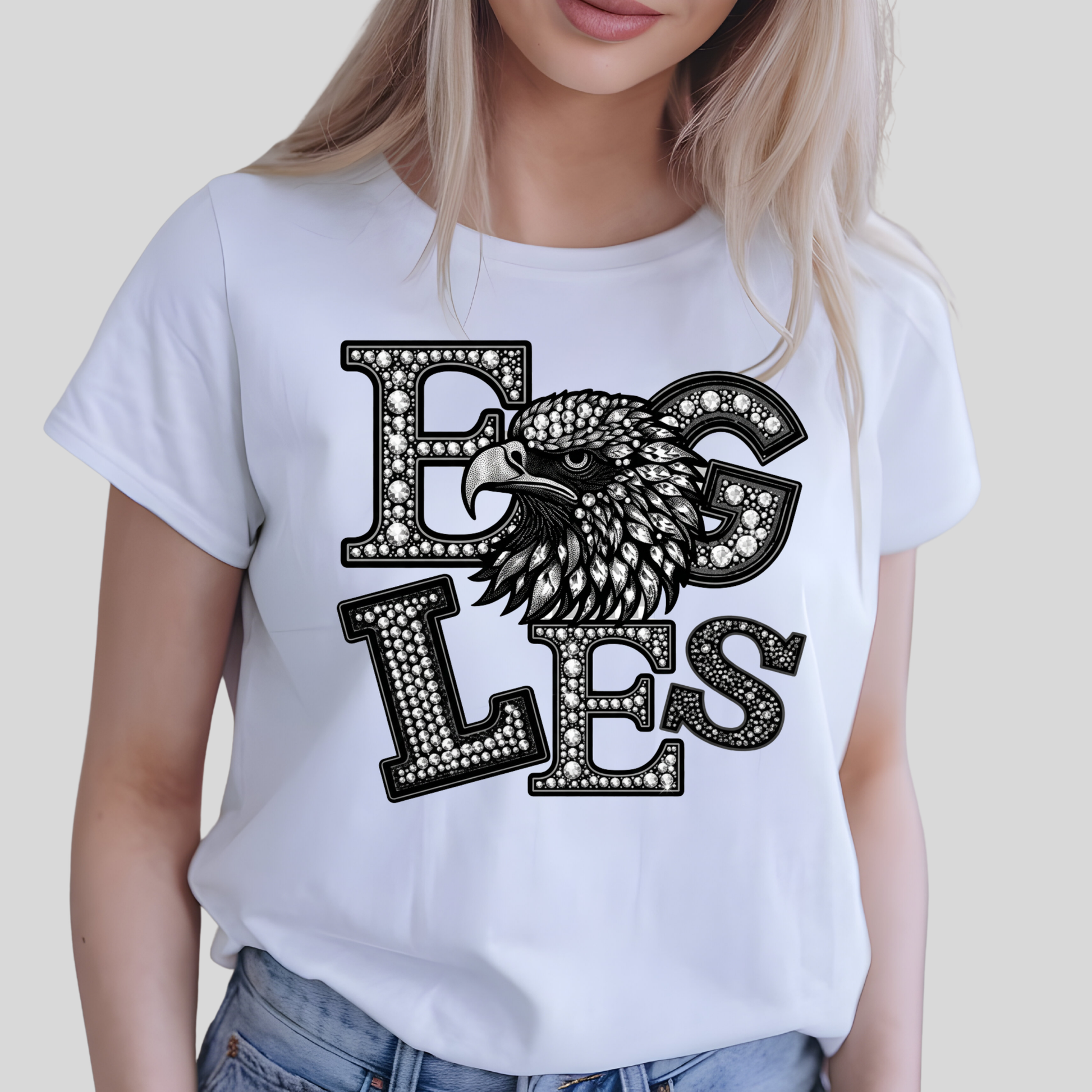 A woman wearing a white short-sleeve t-shirt with a black and white graphic of an eagle's head integrated into the letters 'EGLES'.
