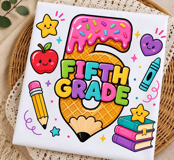 A square white fabric item, likely a napkin or small placemat, printed with a colorful 'Fifth Grade' graphic featuring a pencil, apple, star, books, and crayon on a waffle-textured number 5, styled on a lace doily and wicker tray.