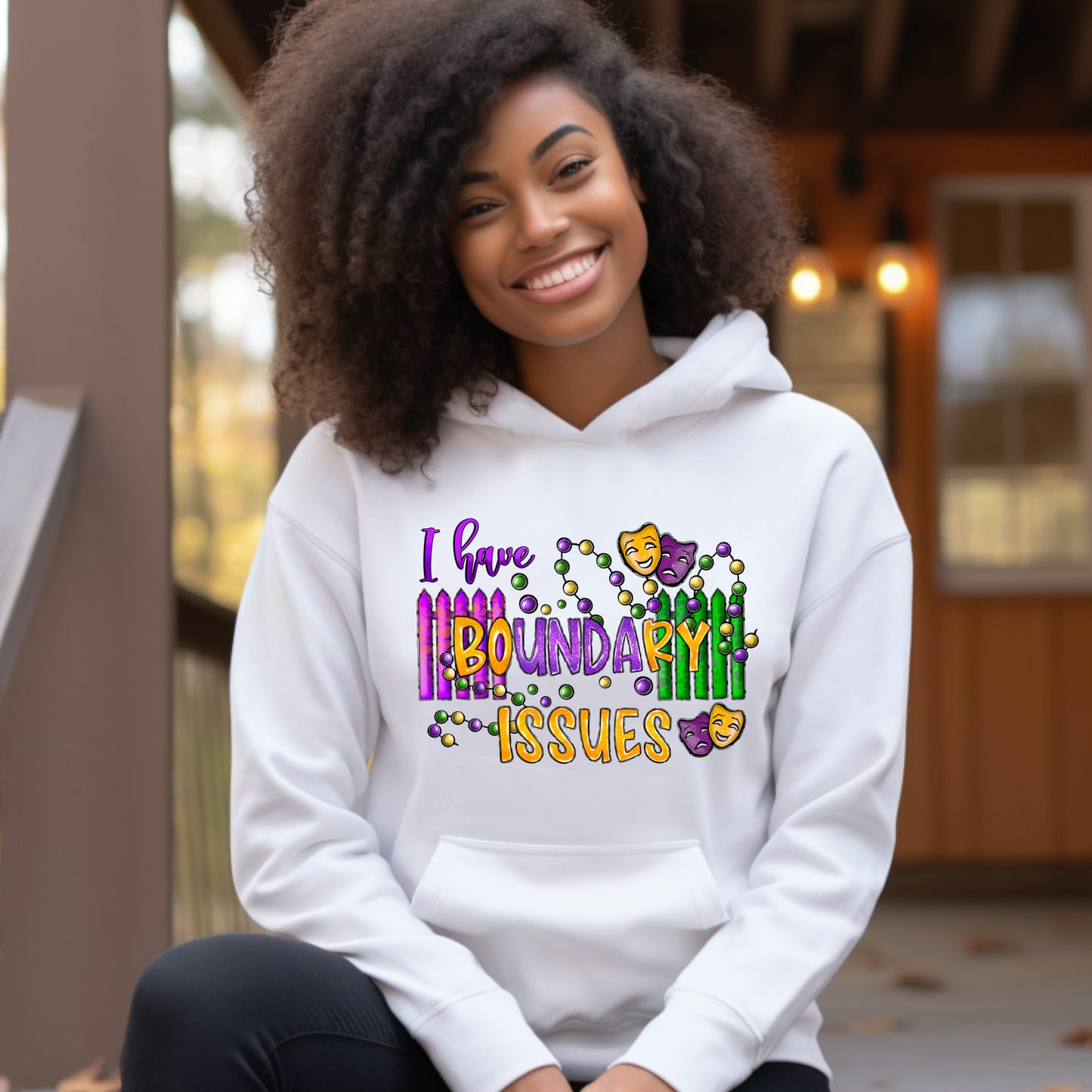 Person wearing a white hoodie with colorful text design sitting outdoors.