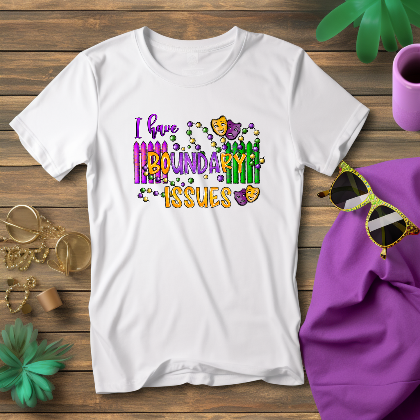 White t-shirt with colorful text and graphics on a wooden surface with accessories.