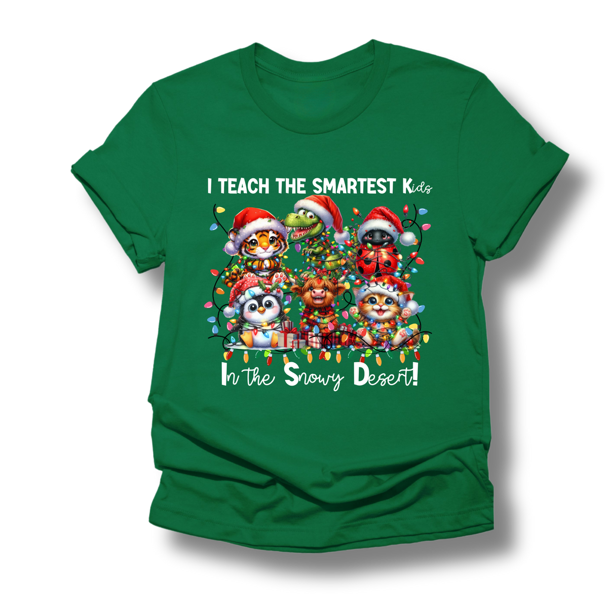 A green short-sleeve crewneck t-shirt with a colorful graphic of Christmas animals and the text 'I TEACH THE SMARTEST Kids In the Snowy Desert!'.