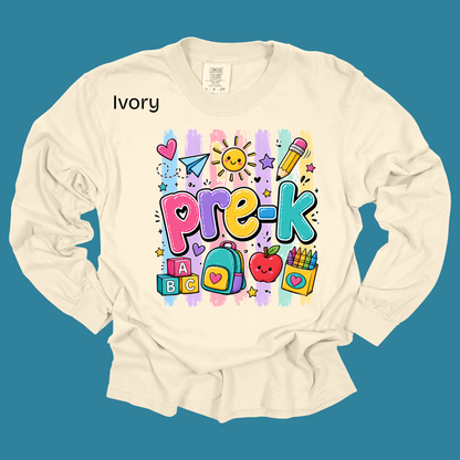 An ivory long-sleeve t-shirt with a colorful 'Pre-K' graphic print on the front, displayed against a solid teal background. The brand 'Ivory' is printed on the upper left chest.