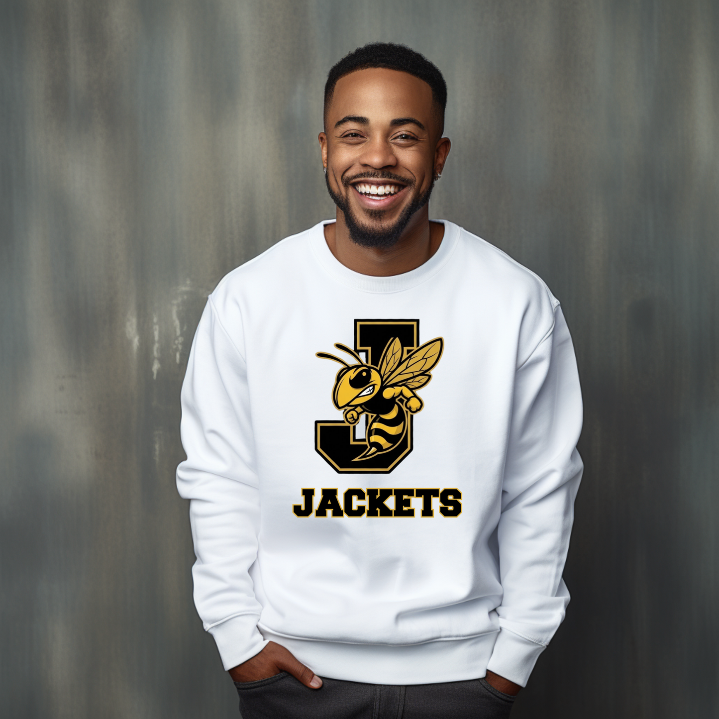 A smiling man wearing a white crewneck sweatshirt with a black and yellow 'J' and bee graphic, with the word 'JACKETS' printed below, set against a textured gray background.
