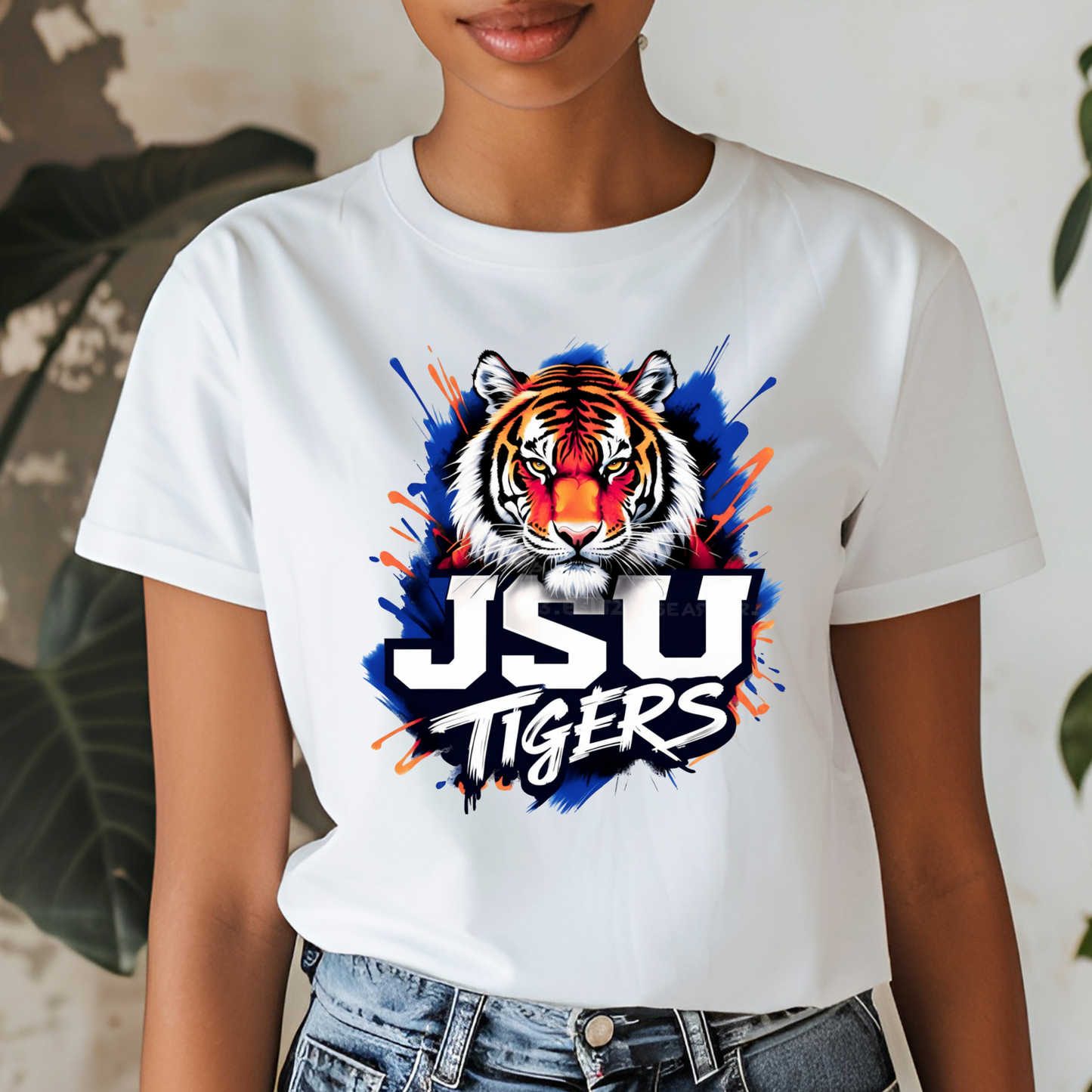A woman wearing a white short-sleeve t-shirt with a colorful graphic of a tiger's face and the text 'JSU TIGERS' in white, blue, and orange paint splatter.