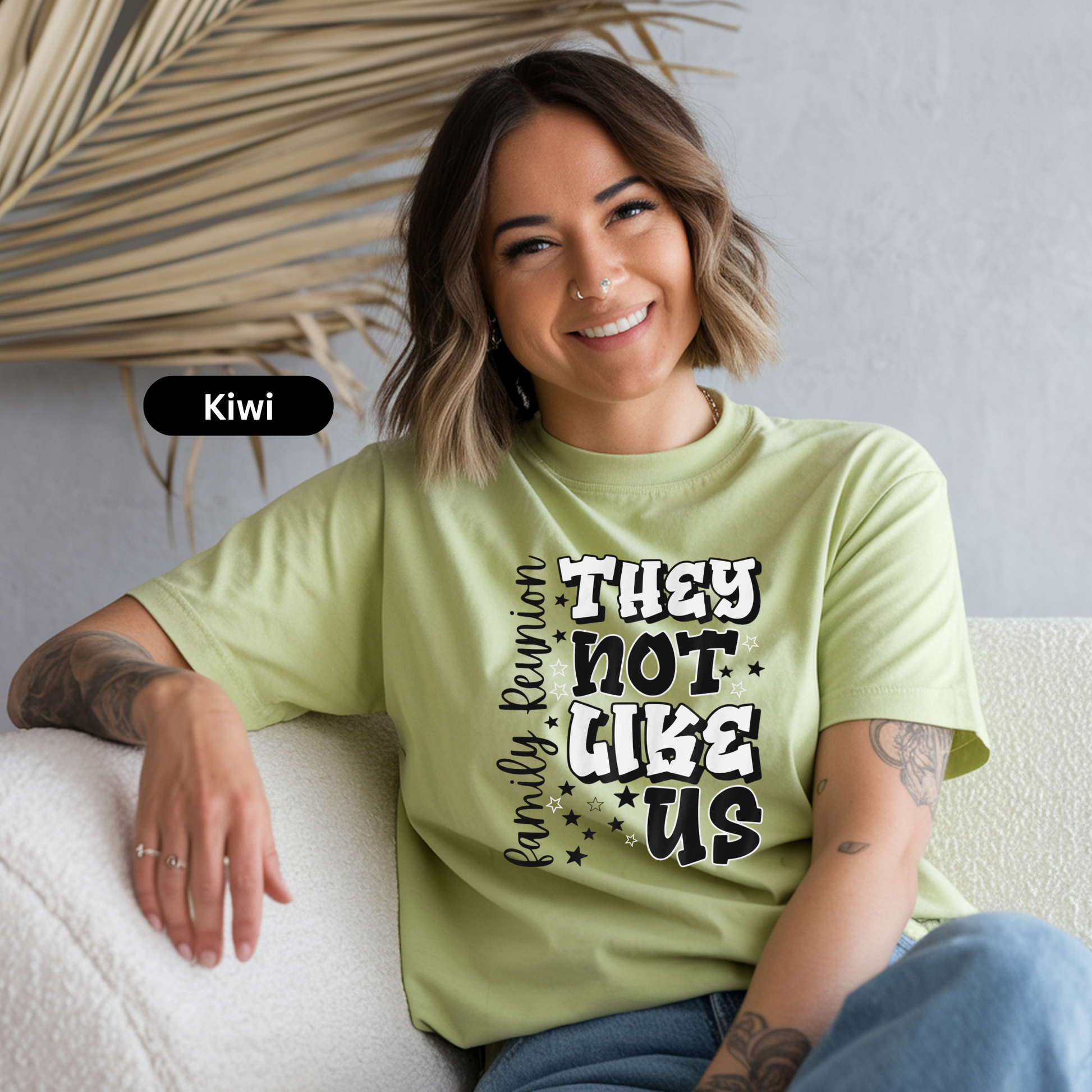 Woman wearing a light green t-shirt with text, sitting on a white couch.