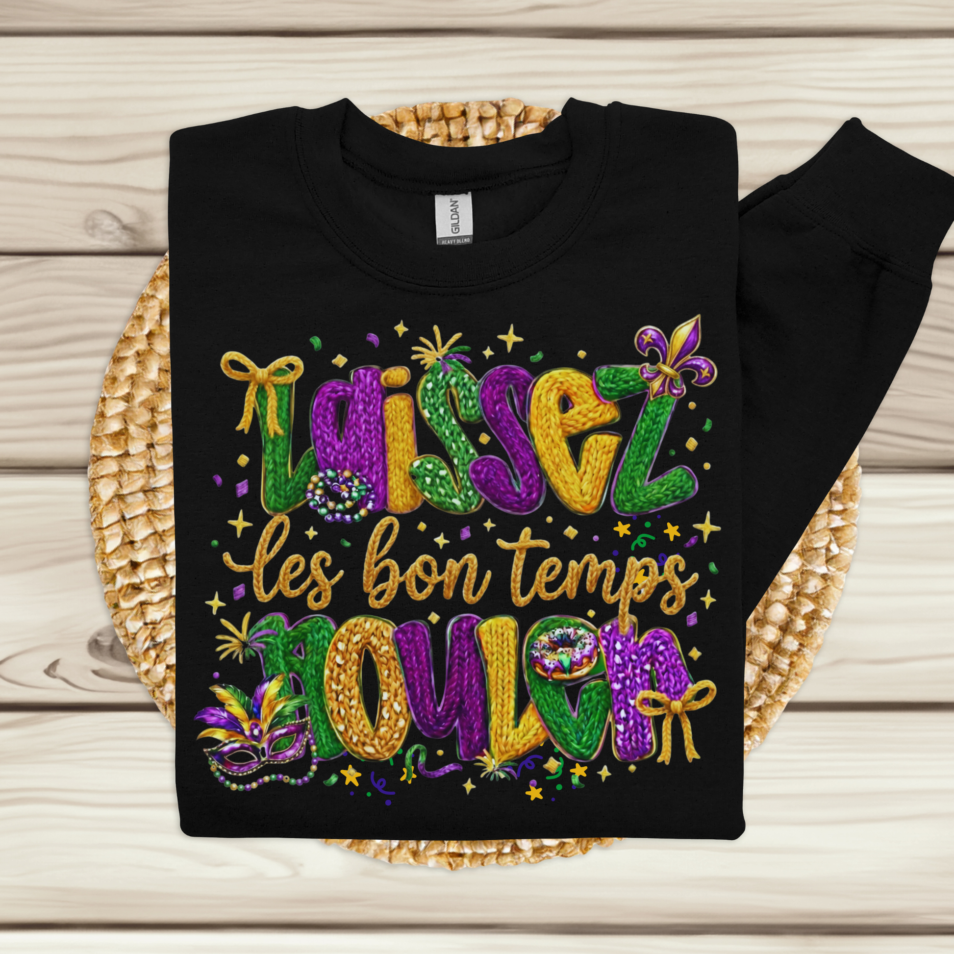 Black sweatshirt with colorful Mardi Gras-themed text and designs on a woven mat.