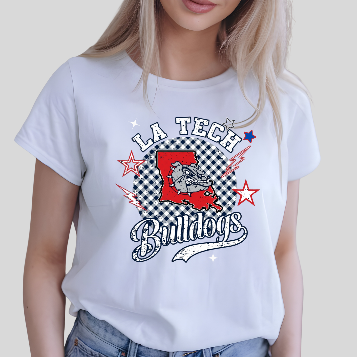 A woman wearing a white graphic t-shirt with a 'LA Tech Bulldogs' design featuring a red bulldog silhouette, black-and-white checkered pattern, and red and blue stars.
