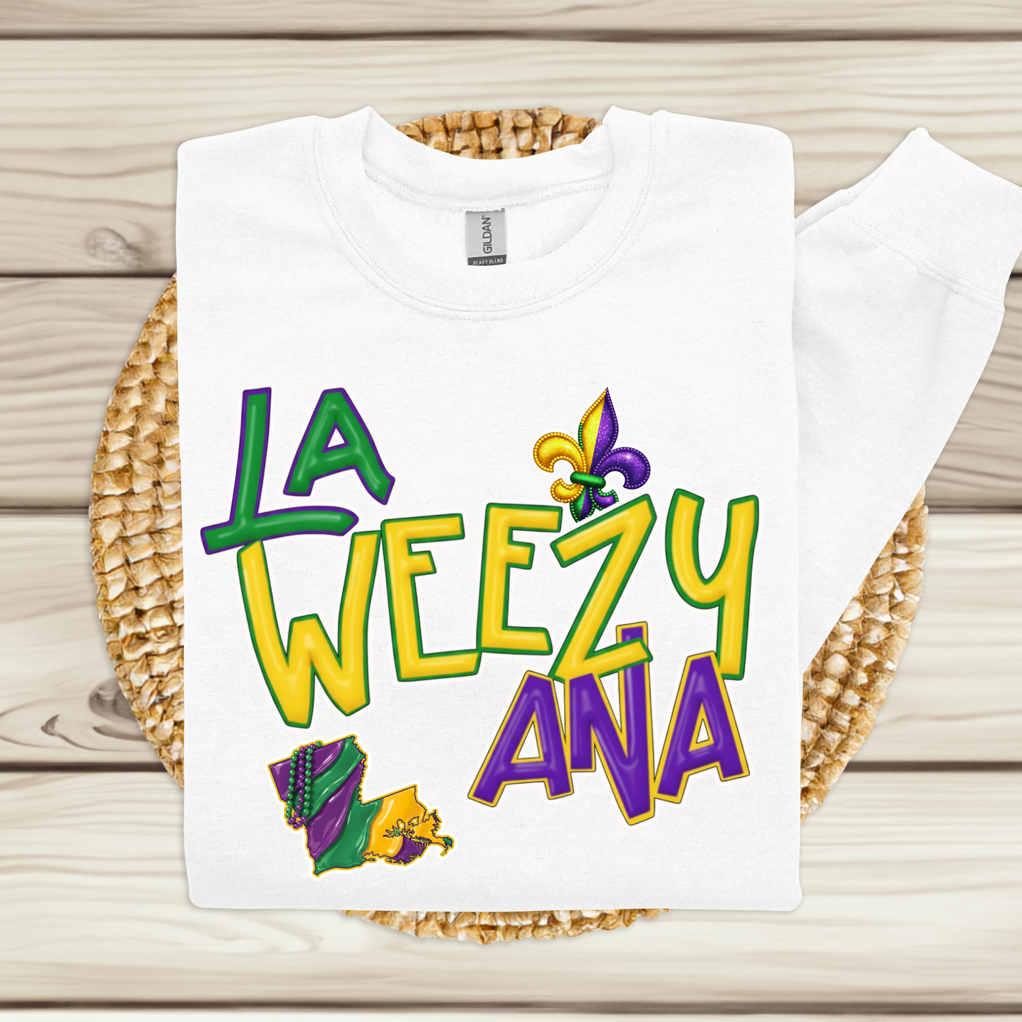 White t-shirt with colorful text and Mardi Gras-themed graphics on a woven mat.